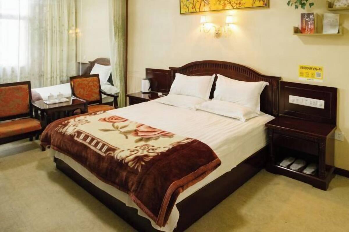 Una habitación de hotel con una cama, una silla, una mesita de noche y una pequeña mesa.