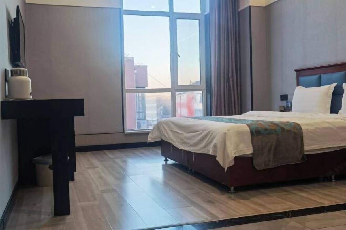 Una camera d'albergo con un letto, una scrivania e un'ampia finestra.