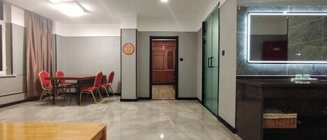 A hotel room with a dining area, a bathroom with a mirror, and a small kitchenette.