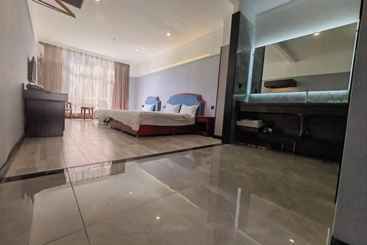 Una camera d'albergo moderna con un letto grande, una scrivania e uno specchio.