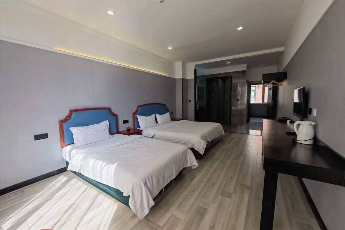 A hotel room with two beds, a desk, a TV, and a coffee maker.