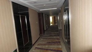 A hotel corridor with a carpeted floor, doors, and a sign indicating the direction to the lobby. - Dihao Hotel (Ruoqiang)