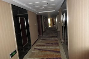 A hotel corridor with a carpeted floor, doors, and a sign indicating the direction to the lobby. - Dihao Hotel (Ruoqiang)