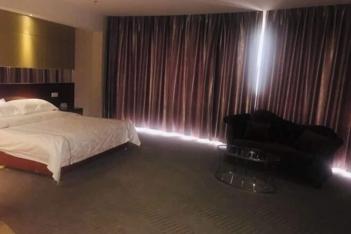 Una habitación de hotel con cama, una mesita y un sofá.