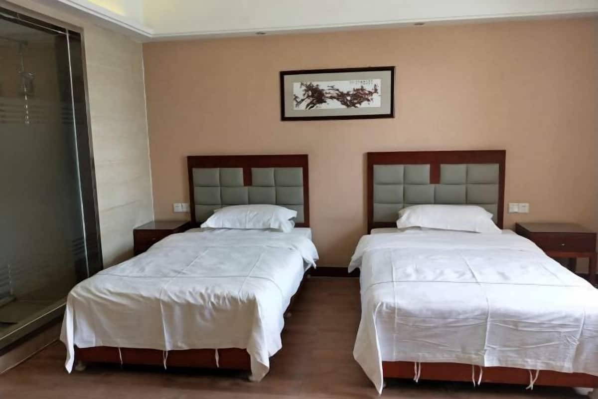 Habitación de hotel con dos camas, un ventanal grande y una obra de arte enmarcada en la pared.
