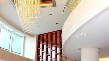 A multi-level interior with a staircase, a decorative ceiling, and a patterned wall.
