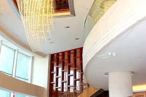 Un intérieur à plusieurs niveaux, avec un escalier, un plafond décoratif et un mur orné de motifs.