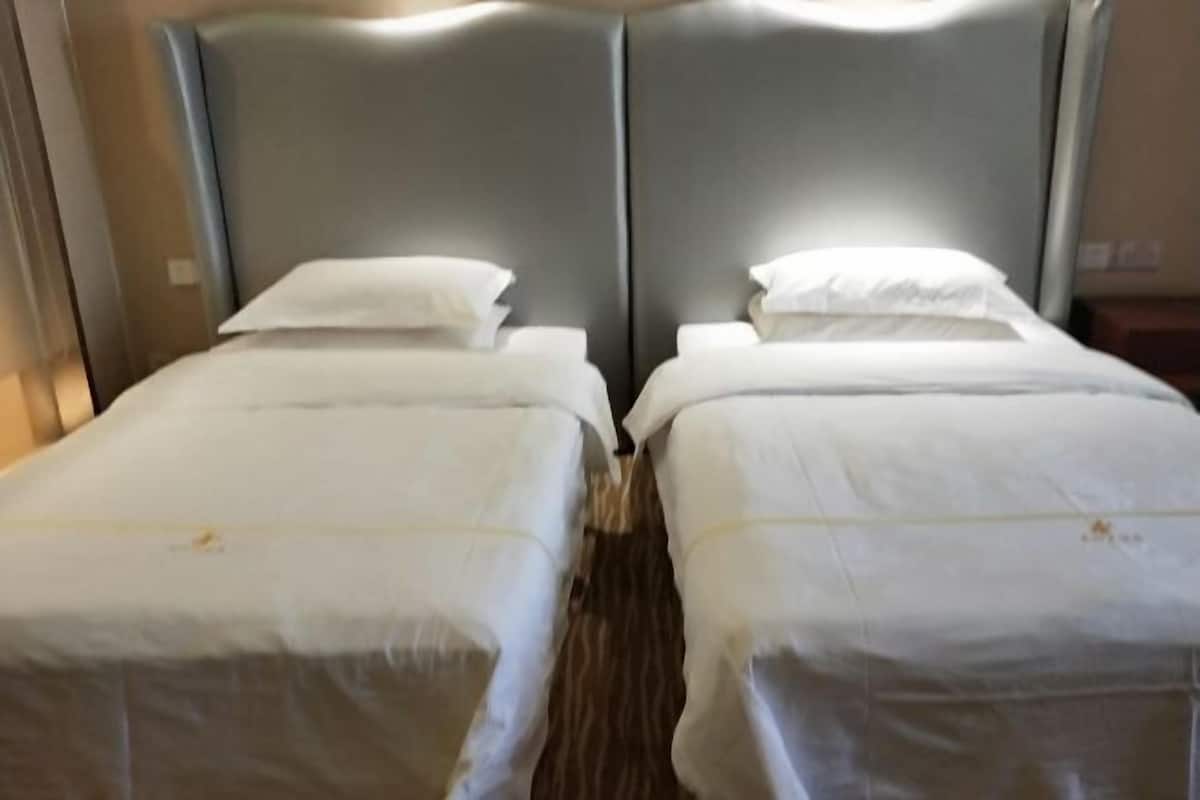 Una cama doble con ropa de cama blanca en una habitación de hotel.