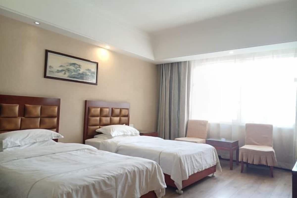Habitación de hotel con dos camas, un escritorio, una silla y un cuadro en la pared.