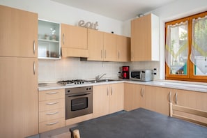 Una cucina moderna con mobili in legno, un fornello a gas, un forno a microonde e una macchina da caffè.