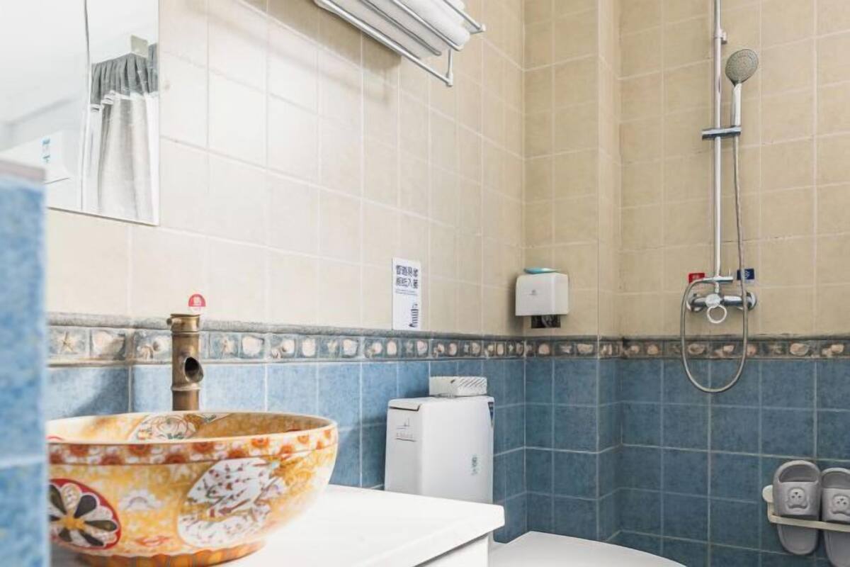 Un baño con un lavamanos decorativo, un cabezal de ducha manual y un perchero para toallas.