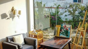 A living room with a sofa, a wooden table, and a painting on an easel.