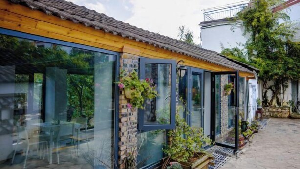 A traditional building with a tiled roof, large glass windows, and potted plants.