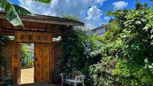 A wooden structure with a sign, surrounded by lush greenery and a clear sky.