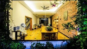 A dining area with a brick wall, a ceiling fan, and a table with chairs.