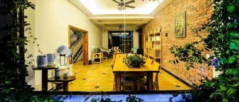 A dining area with a brick wall, a ceiling fan, and a table with chairs.