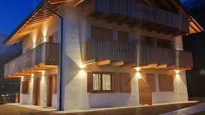 Een gebouw met twee verdiepingen, een balkon op de bovenverdieping, een overdekte veranda op de begane grond en een zichtbare schoorsteen.