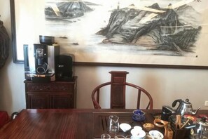 A dining area with a wooden table, chairs, a coffee machine, and a painting on the wall. - Wanting Hotel (Shanghai Xinchang ancient town store) (Shanghai)