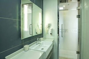 A modern bathroom with two sinks, a large mirror, and a glass shower enclosure. - Wanting Hotel (Shanghai Xinchang ancient town store) (Shanghai)