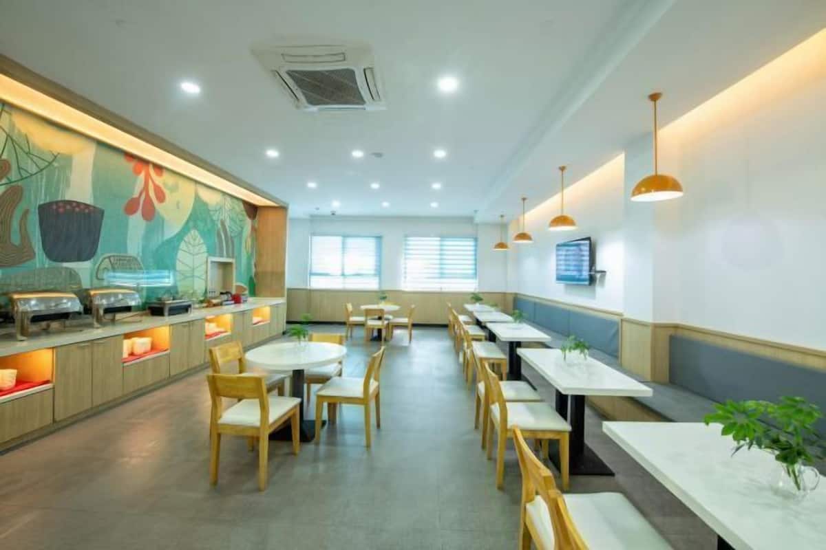A modern restaurant with wooden tables and chairs, a long counter with food displays, and a mural on the wall.