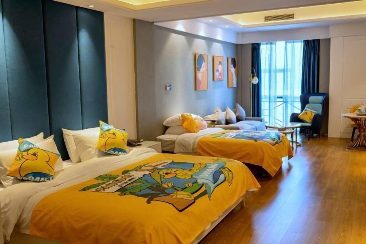 A hotel room with two beds, a desk, a chair, and artwork on the wall.