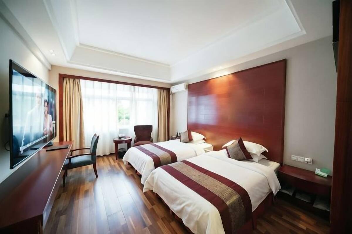 A hotel room with two beds, a TV, a desk, and a chair.