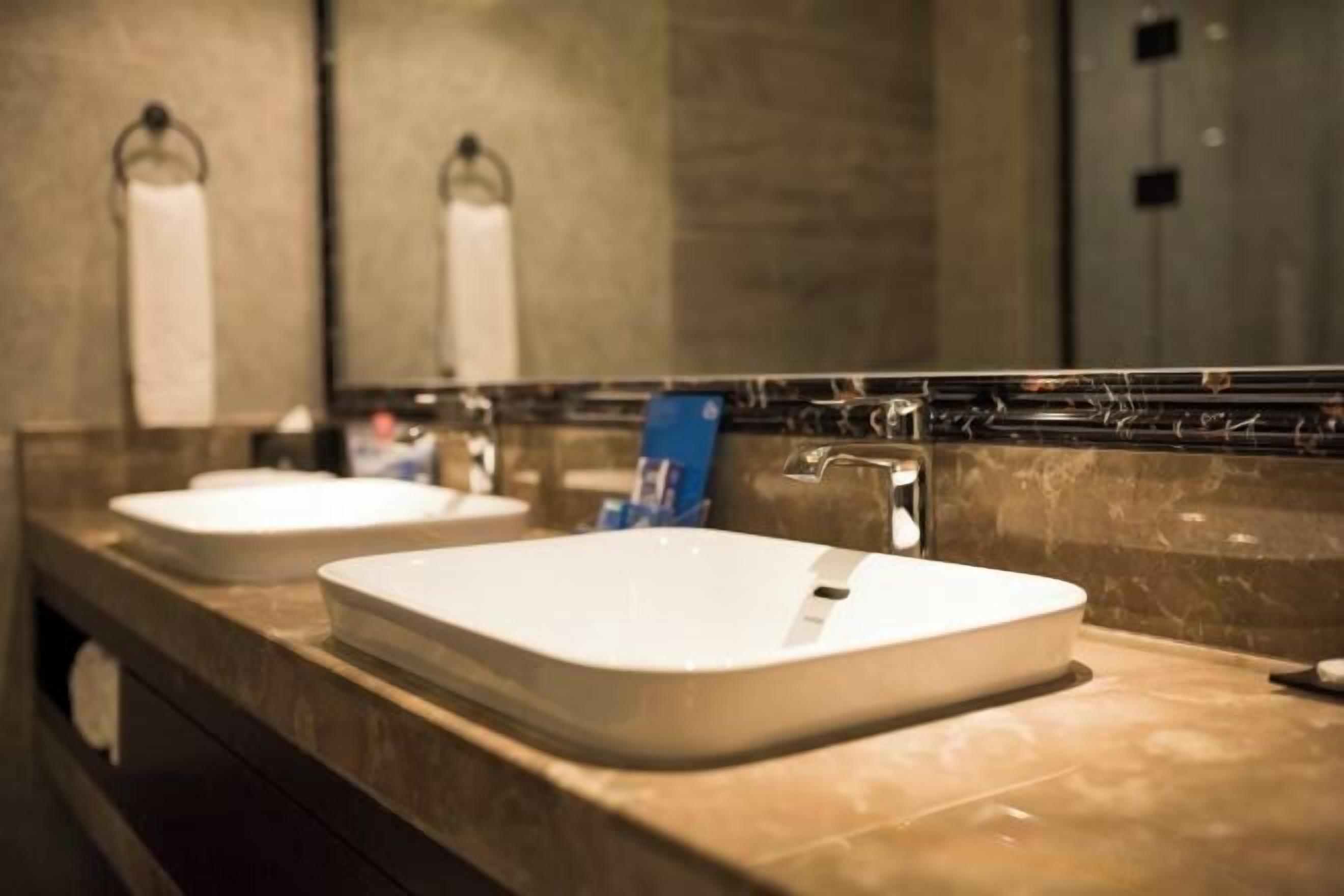 A bathroom with two white sinks, a mirror, and a towel rack.