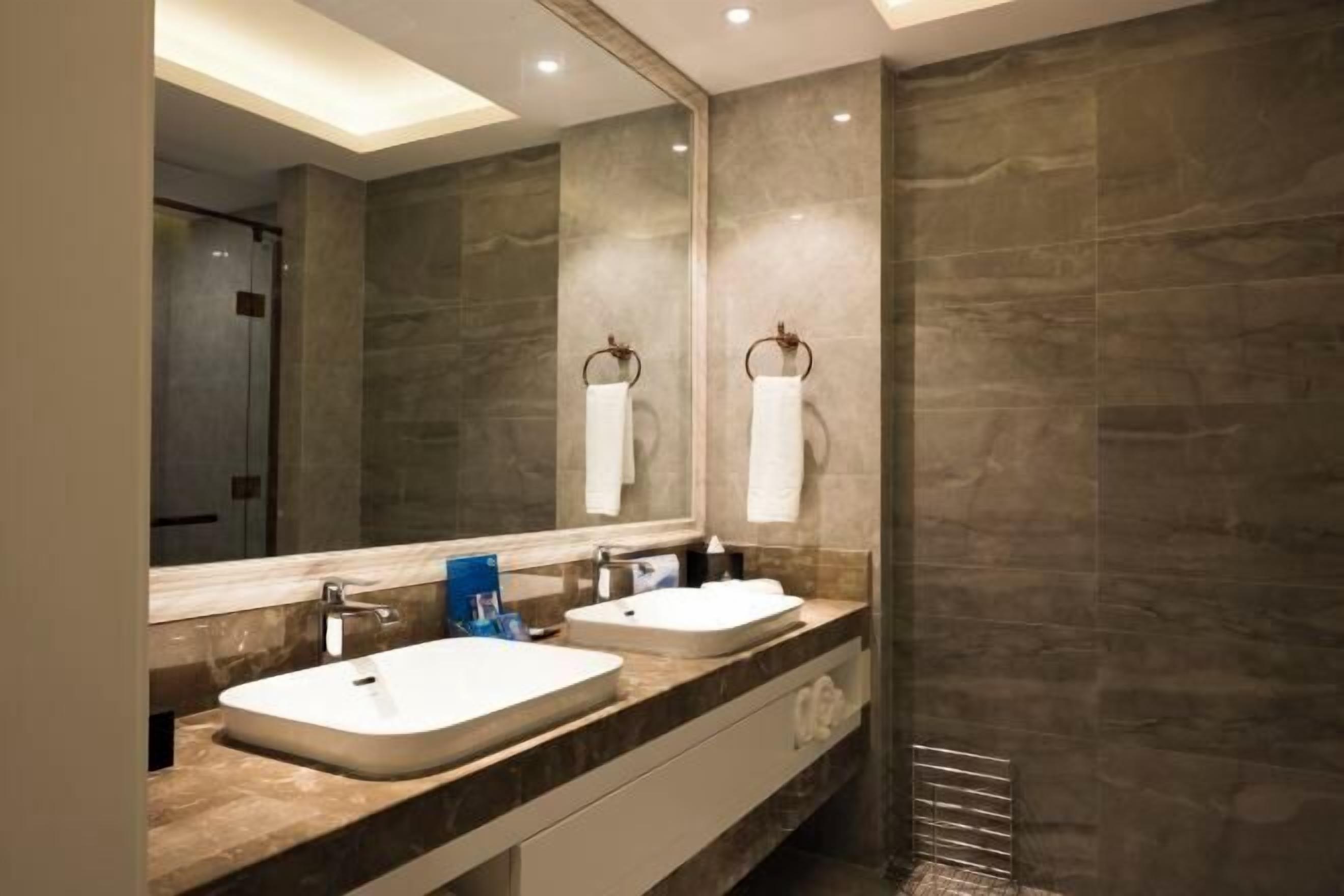 A modern bathroom with two sinks, a large mirror, and a towel rack.