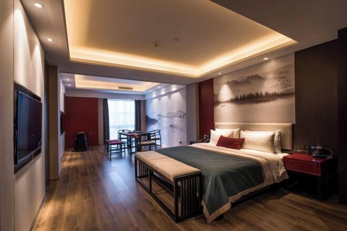 A modern hotel room with a large bed, a desk, and a seating area.