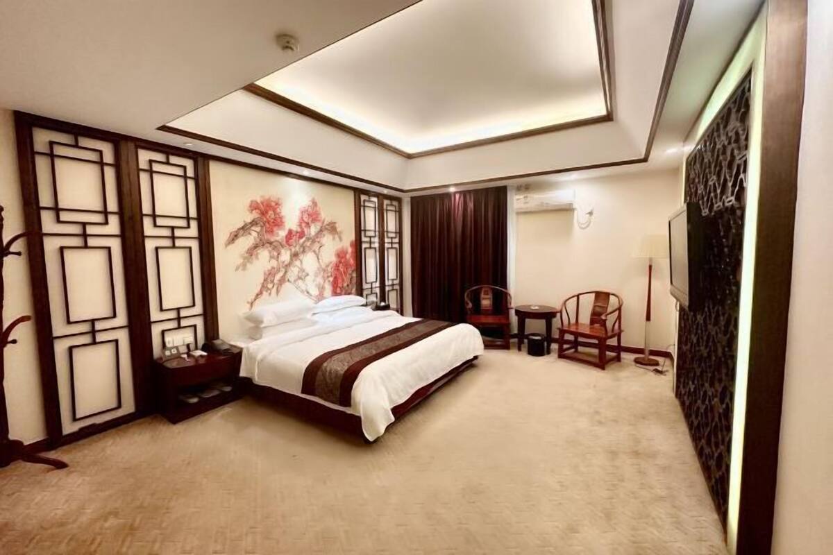 A hotel room with a large bed, a desk, a chair, and a decorative wall.