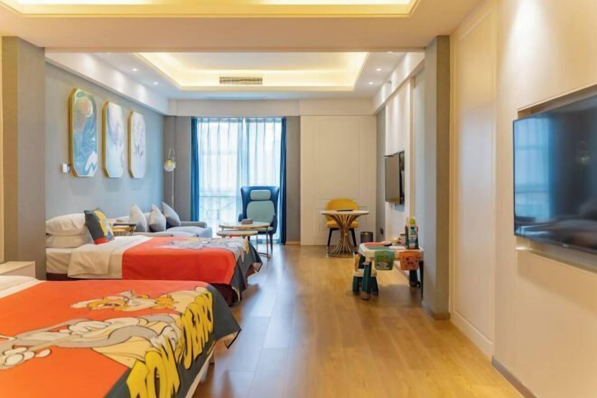 A hotel room with two beds, a TV, a desk, and a chair.