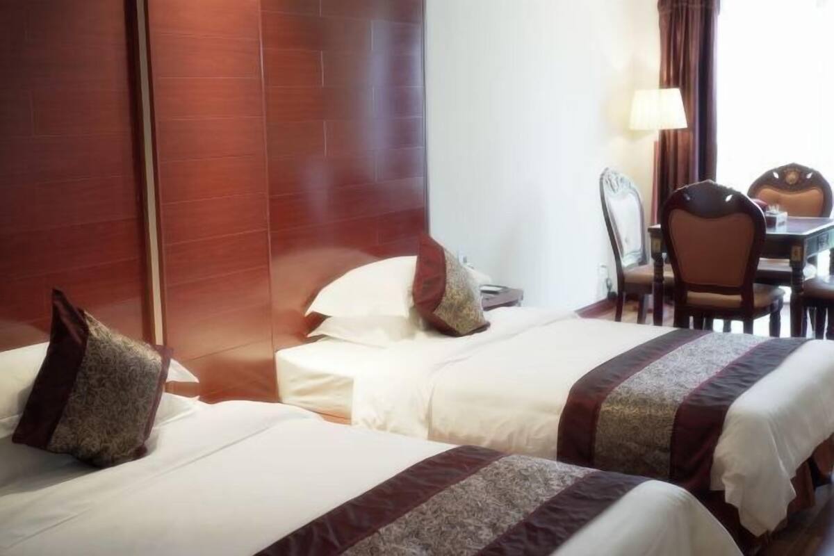 A hotel room with two beds, a desk, and a chair.
