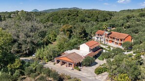 Una propietat rural amb diversos edificis, un carrer pavimentat i vegetació al voltant.