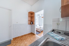 A kitchen with a tiled floor, a wooden shelf, a sink, and a countertop. - Studio Apartment 'Maltas 6' with Shared Terrace, Wi-Fi and Air Conditioning (Corfu)