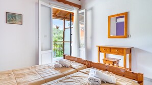 A bedroom with two beds, a wooden headboard, a small wooden table, a mirror, and an open door leading to a balcony. - Studio Apartment 'Maltas  17' with Shared Terrace, Wi-Fi and Air Conditioning (Corfu)
