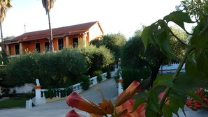A building with a red roof and white walls, surrounded by greenery and a paved pathway. - Studio Apartment 'Maltas  17' with Shared Terrace, Wi-Fi and Air Conditioning (Corfu)