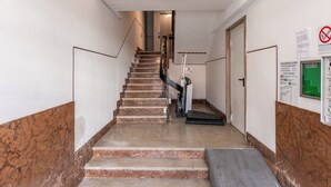 A staircase with marble steps, a handrail, and a green emergency exit sign.