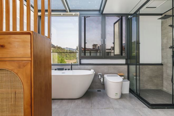 Un baño moderno con una bañera independiente, una ducha con cerramiento de vidrio y un inodoro.