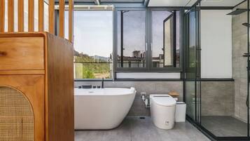 Un baño moderno con una bañera independiente, una ducha con cerramiento de vidrio y un inodoro.