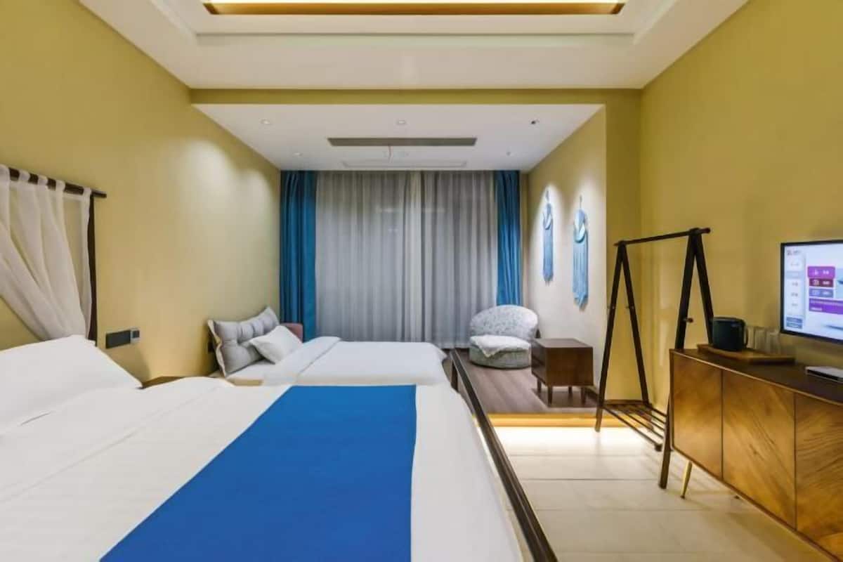A hotel room with two beds, a TV, a desk, and a chair.