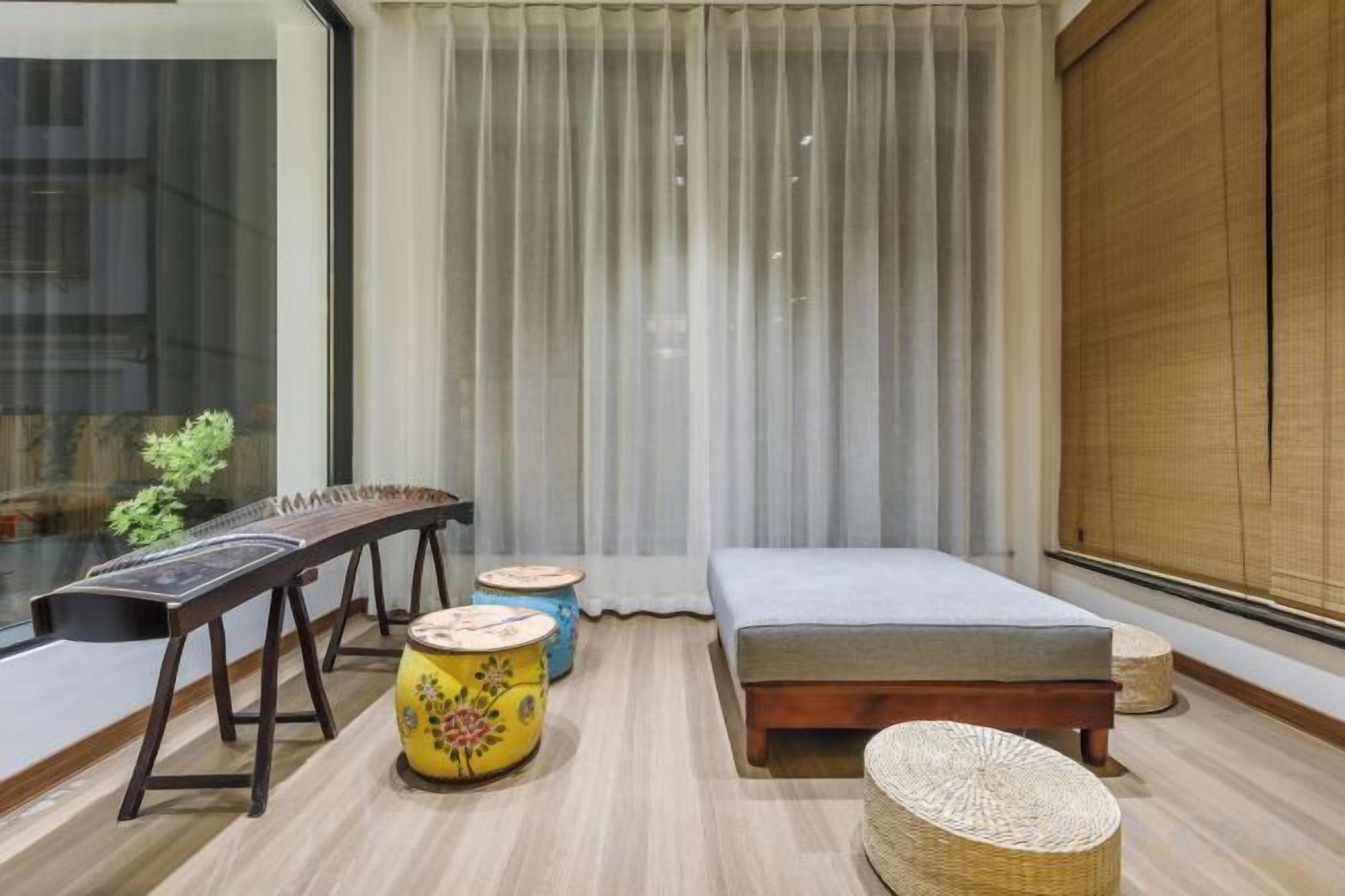 Una habitación con cama, una mesita y una ventana con cortinas.