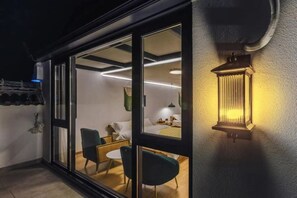 Un interior moderno con una puerta de vidrio que da a una habitación con cama, una silla y una mesa.