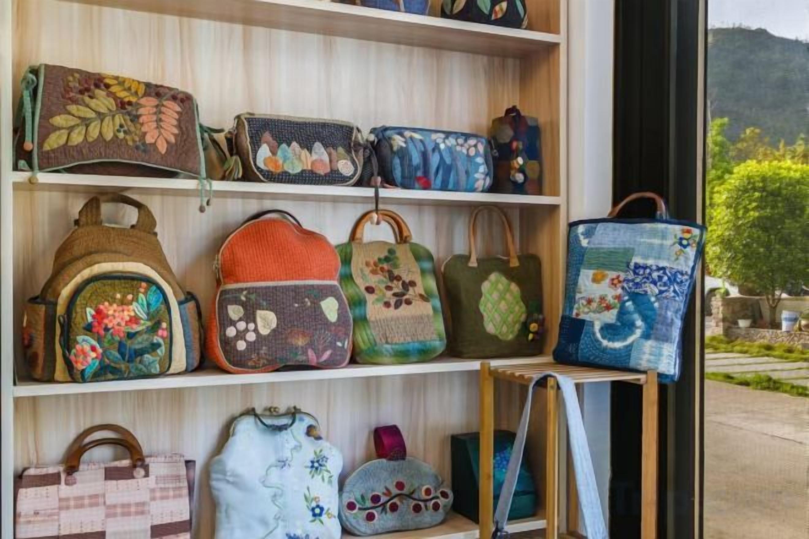 A display of various handbags on shelves.