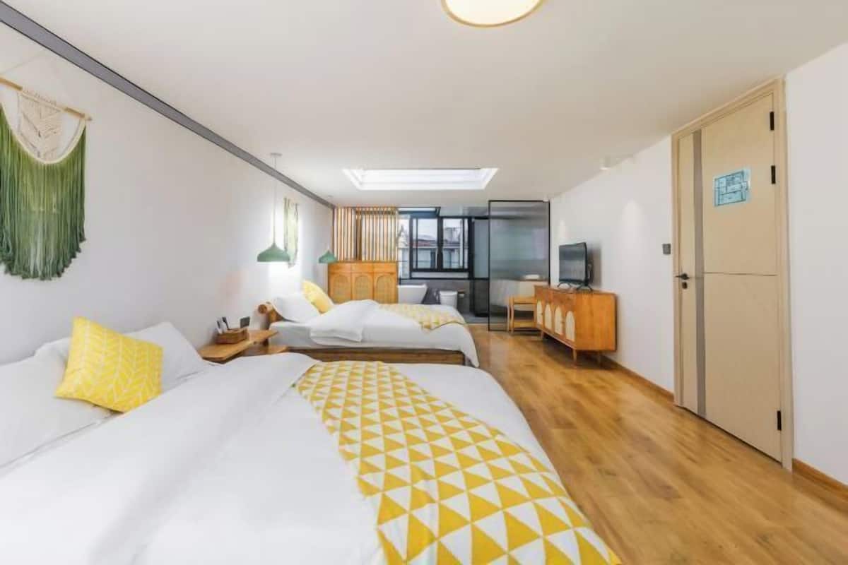 A hotel room with two beds, a TV, a wardrobe, and a desk.
