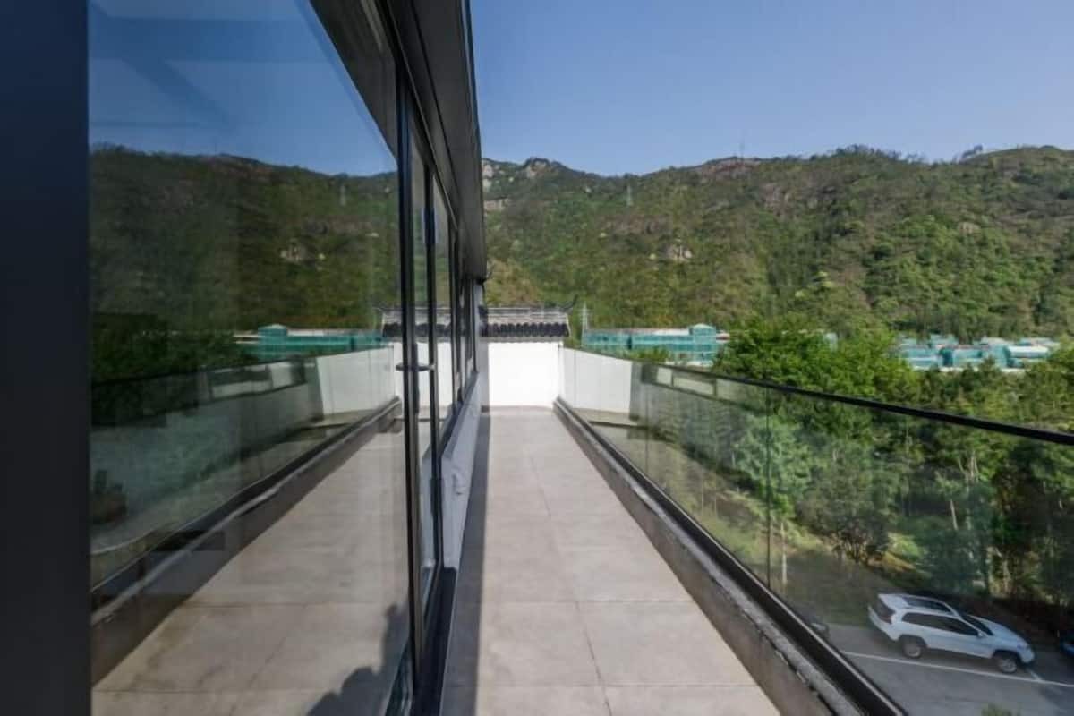 A balcony with a view of a parking area and a hilly landscape.