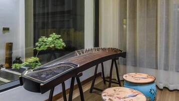 Un instrument à cordes traditionnel posé sur un support, une petite plante en pot et deux tambours décoratifs.