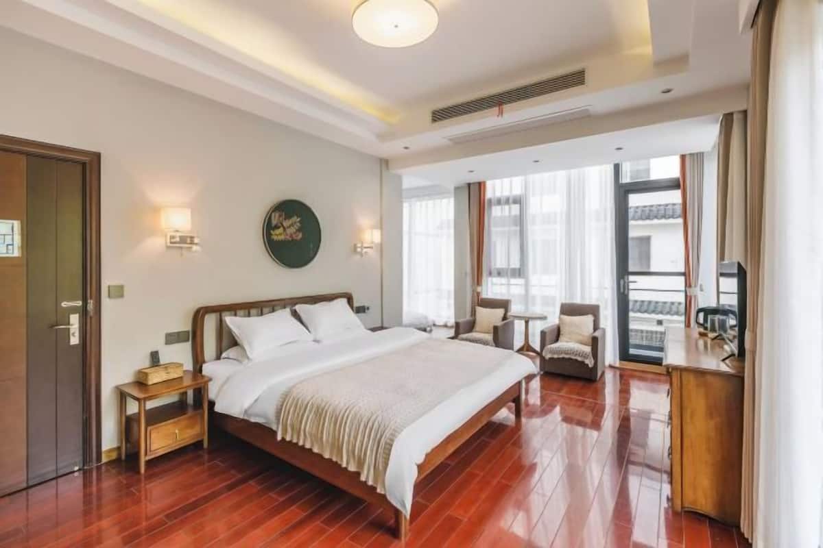 A hotel room with a wooden bed, bedside tables, a desk, and a view of the outside.