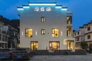 A multi-story hotel with illuminated signage, a parking area, and a stone facade.