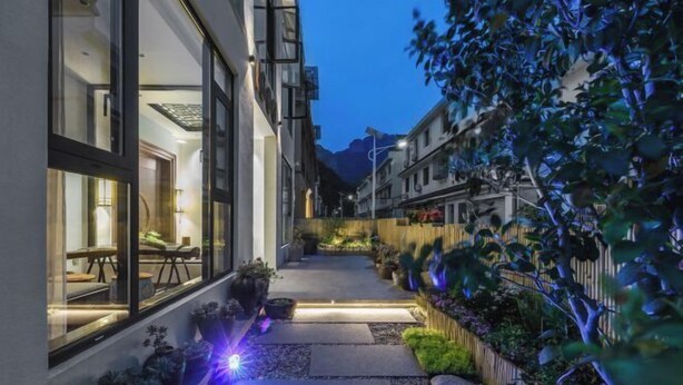 A narrow pathway flanked by buildings with large windows, leading to a seating area with outdoor furniture. - Tingxiju Inn (Xianju)