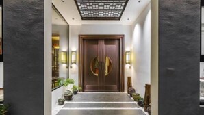 A modern hotel entrance with a wooden door, steps leading up to it, and potted plants along the sides. - Tingxiju Inn (Xianju)